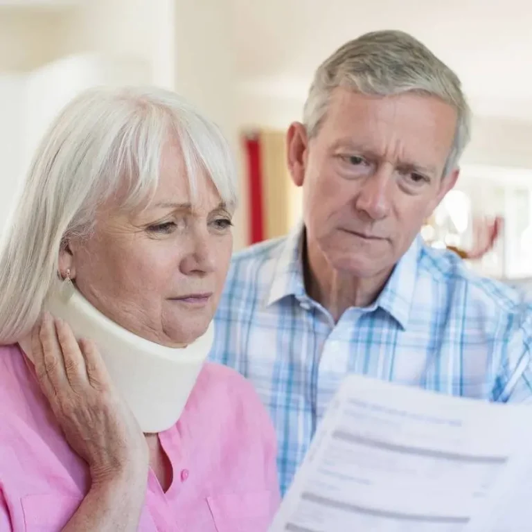 Concerned elderly couple reviewing paperwork after a car accident, woman wearing a neck brace – Peoria car accident settlement delays.